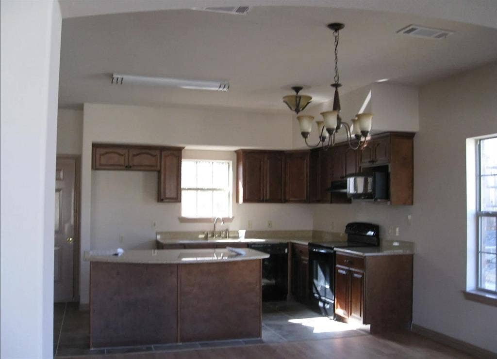 2514 Apollo Villa Road, Garland, TX 75044 Kitchen featuring dark wood-finish cabinetry, light-toned countertops, a multi-light chandelier, and integrated appliances