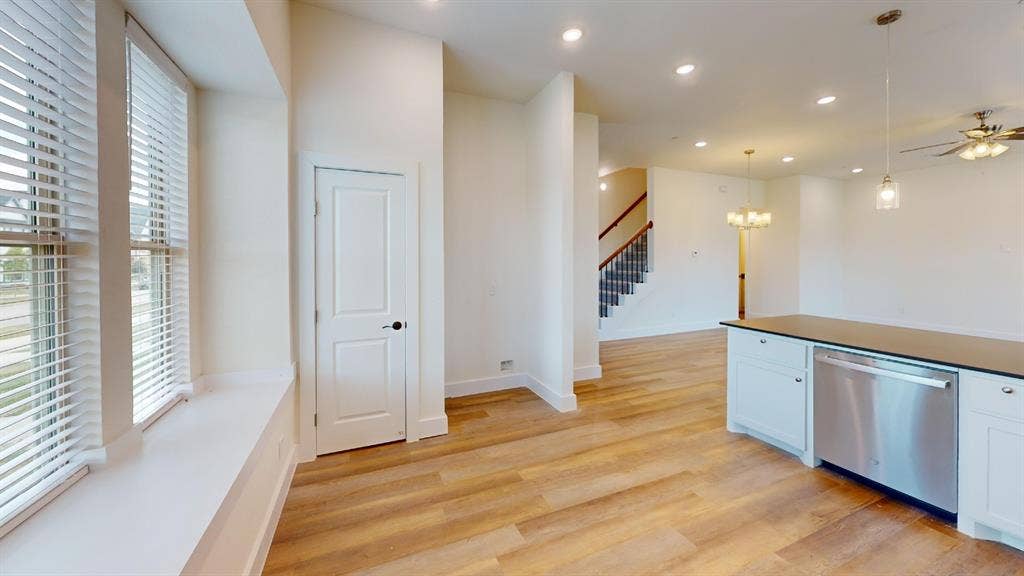 373 Buck Ridge Drive, Frisco, TX 75068 Wood-finish flooring, recessed lighting, and a stainless steel dishwasher integrated into white cabinetry with a dark countertop