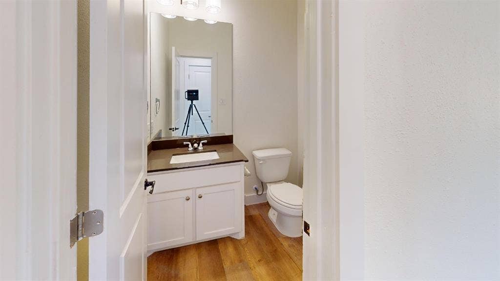 373 Buck Ridge Drive, Frisco, TX 75068 White vanity with a dark countertop, undermount sink, and wood-finish flooring
