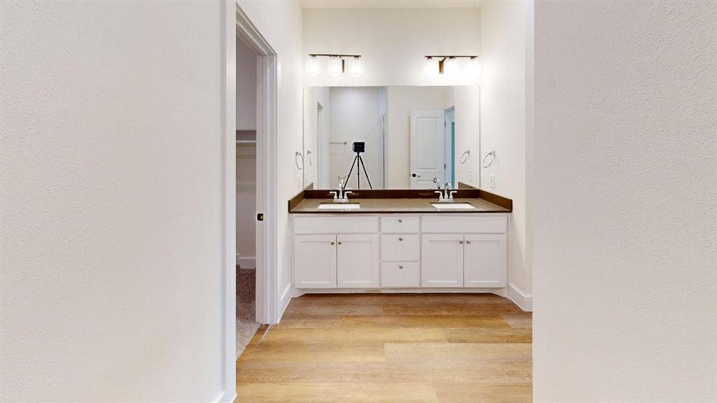 373 Buck Ridge Drive, Frisco, TX 75068 Dual vanity with integrated sinks, dark countertop, and wood-finish flooring
