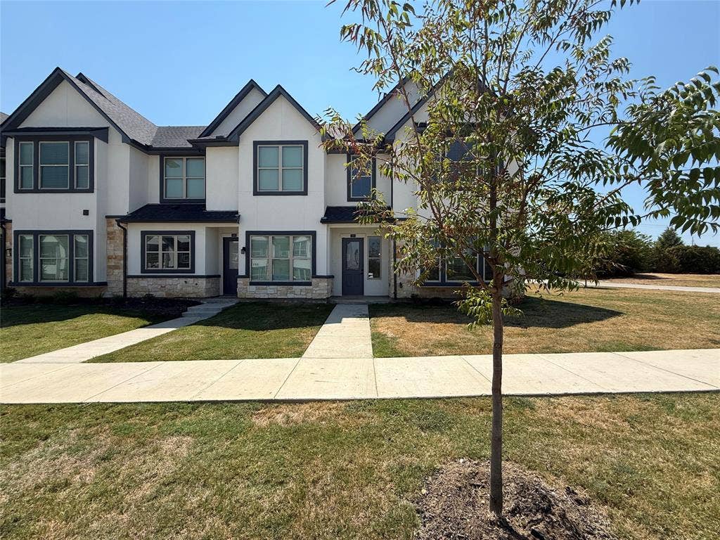 373 Buck Ridge Drive, Frisco, TX 75068 Modern townhome architecture featuring multiple gables, dark window trim, stone veneer accents, and a dark shingled roof