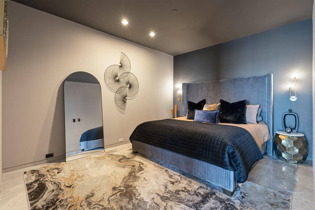 Recessed lighting illuminates a feature wall with sconces, complemented by a textured headboard