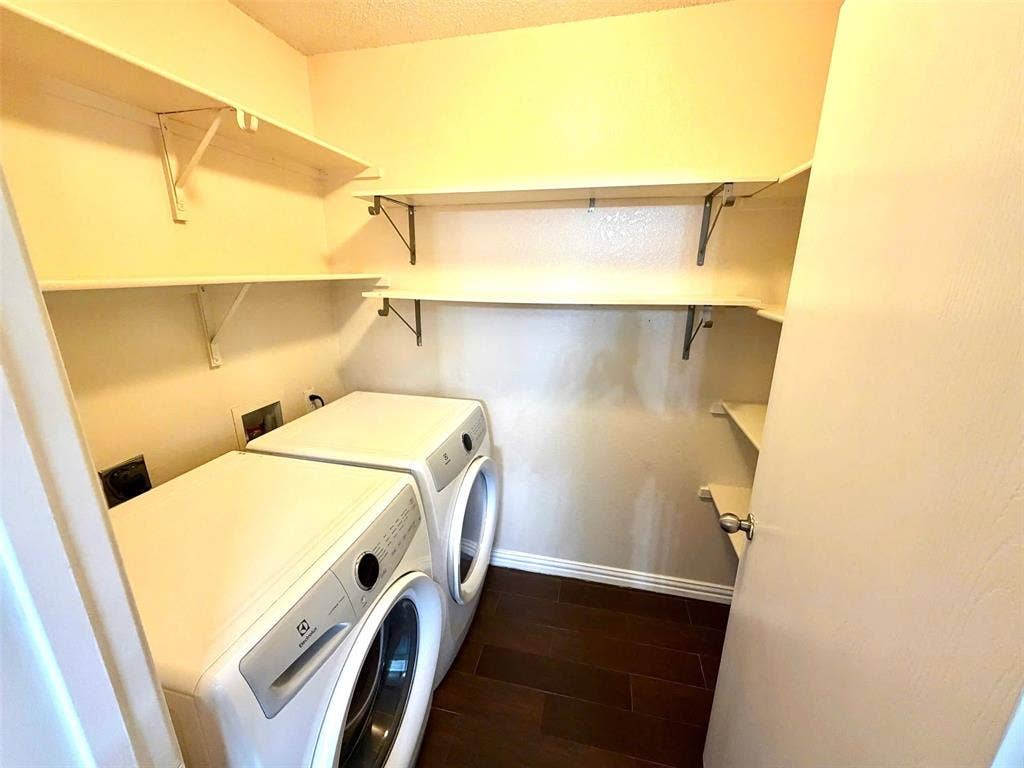 Laundry area featuring wood-finish flooring and multiple wall-mounted shelves