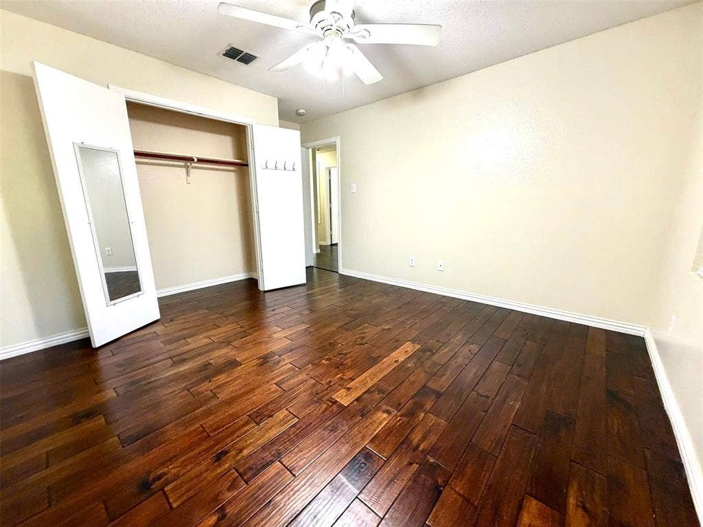 Rich wood-finish flooring, ceiling fan with integrated lighting, and a closet with bifold doors