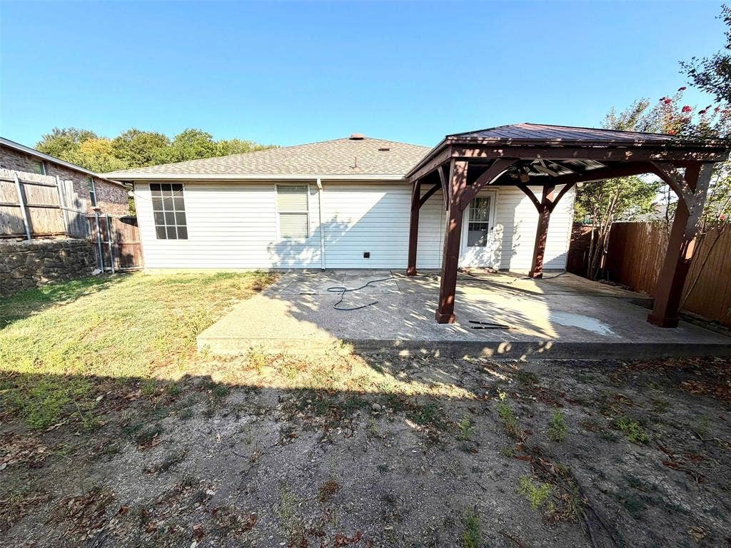 Rear exterior with white siding, covered concrete patio, and a shingled roof