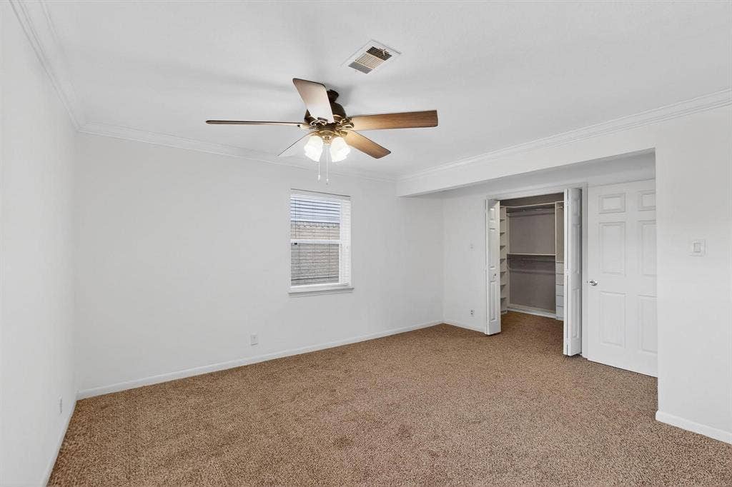 2927 Selma Lane, Farmers Branch, TX 75234 Unfurnished bedroom featuring ornamental molding, carpet flooring, ceiling fan, a walk in closet, and a closet