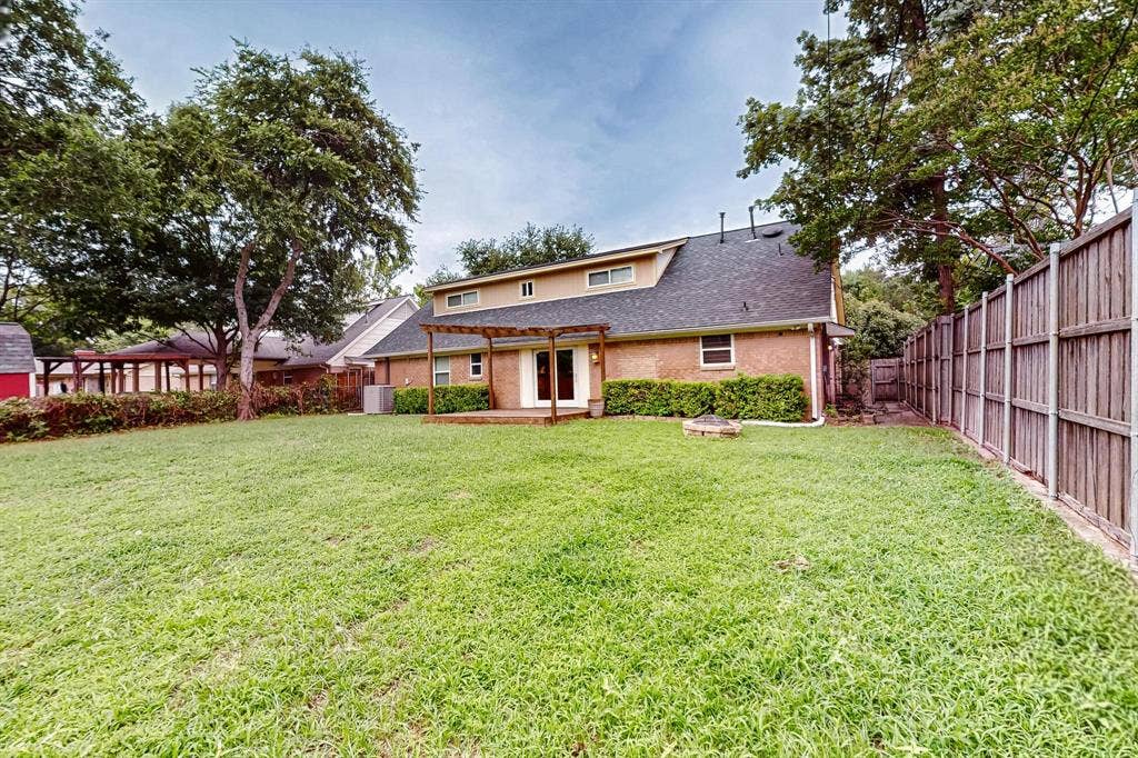 2927 Selma Lane, Farmers Branch, TX 75234 Back of property featuring a fenced backyard, a pergola, and a shingled roof