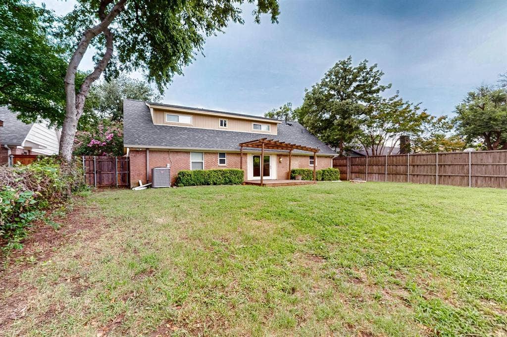 2927 Selma Lane, Farmers Branch, TX 75234 Rear view of house featuring a pergola, a fenced backyard, brick siding, roof with shingles, and a patio