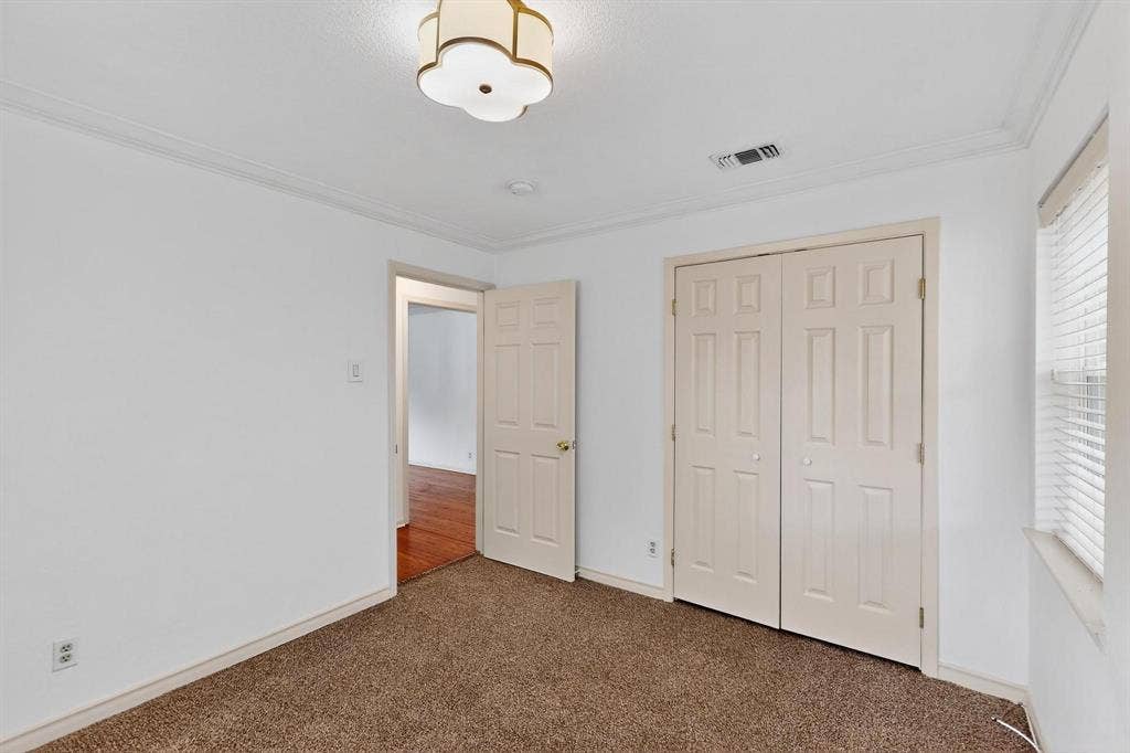 2927 Selma Lane, Farmers Branch, TX 75234 Unfurnished bedroom with carpet flooring, crown molding, a closet, and multiple windows