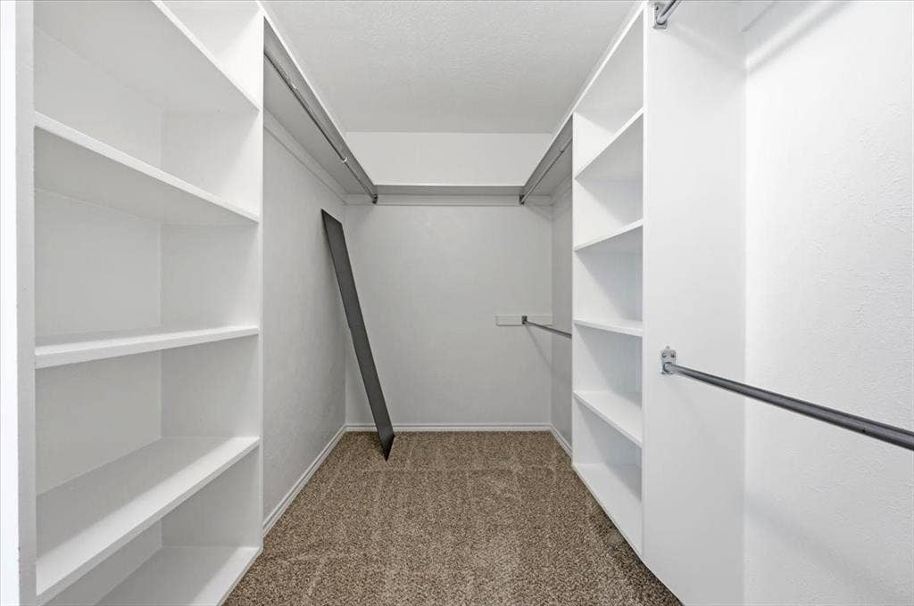Primary bedroom closetwith shelves and rods