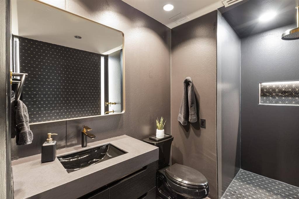 2430 Victory Park Lane, #2401, Dallas, TX 75219 Vanity with an integrated black sink and gold-tone faucet, complemented by a gold-framed mirror