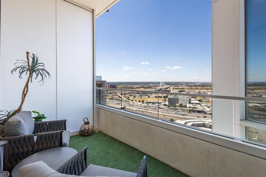 2430 Victory Park Lane, #2401, Dallas, TX 75219 Balcony with glass railing, turf-covered flooring, and surrounding cityscape