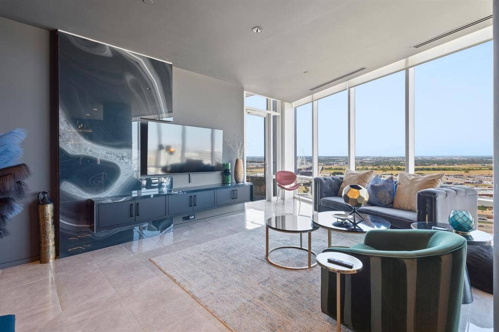 2430 Victory Park Lane, #2401, Dallas, TX 75219 Expansive floor-to-ceiling windows, large format tile flooring, a wall-mounted media console, and a striking accent wall