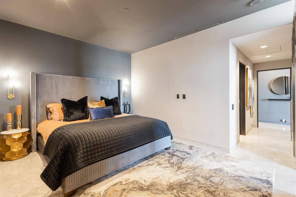 2430 Victory Park Lane, #2401, Dallas, TX 75219 Accent wall with sconce lighting, sleek wall-mounted outlets, overhead recessed lighting, and polished stone tile flooring