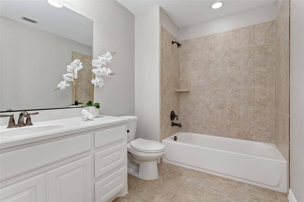 844 Veneto Drive, Allen, TX 75013 Full bath with a tub and shower combination in a tile surround, a single vanity with white cabinetry, andtile flooring. Oil-rubbed bronze fixtures.