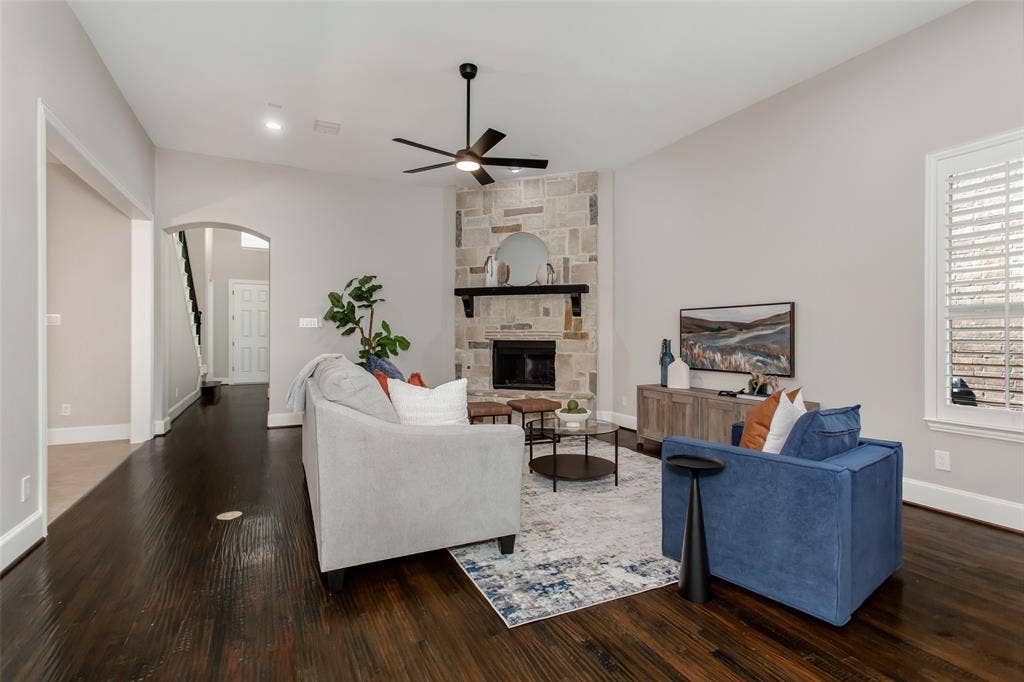844 Veneto Drive, Allen, TX 75013 View toward the stone fireplace, with an arched opening to the foyer and staircase. Recessed lightingand a new 2026 ceiling fan with an LED light overhead.