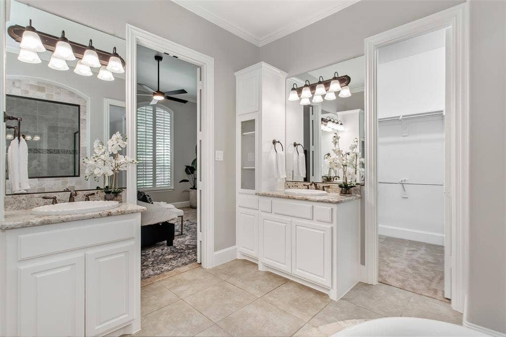844 Veneto Drive, Allen, TX 75013 Two separate vanities with granite counters and a linen tower with open shelving. Doorways to thewalk-in closet and the primary bedroom.