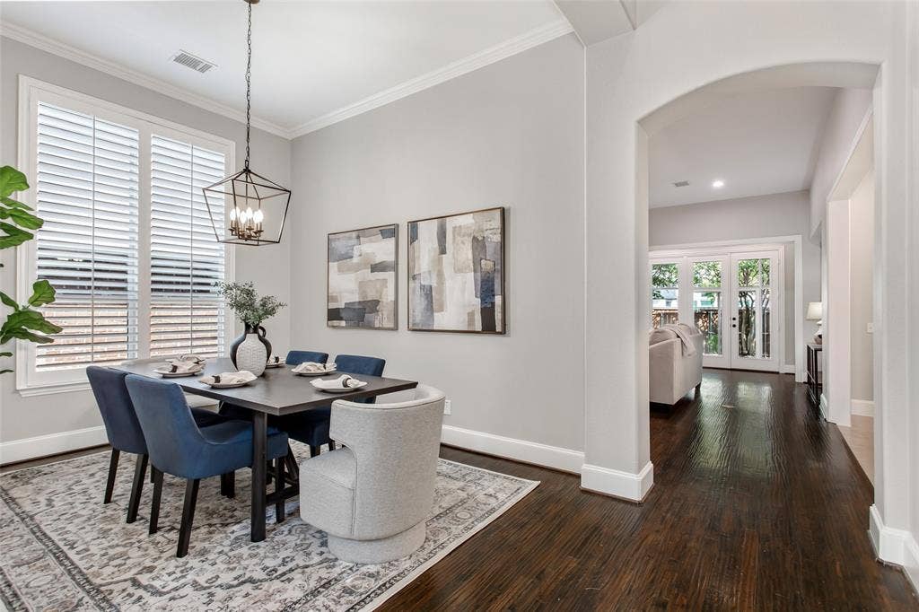 844 Veneto Drive, Allen, TX 75013 Dining room with crown molding, plantation shutters on oversized windows, and a new 2026 lanternchandelier. An arched opening and hardwood hallway lead to the family room.