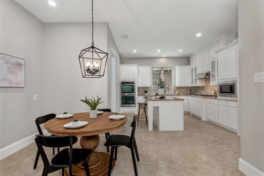 844 Veneto Drive, Allen, TX 75013 Breakfast nook with tile flooring and a new 2026 lantern pendant opens to the kitchen. Stainless doublewall ovens, a center island, and white cabinetry with crown molding.