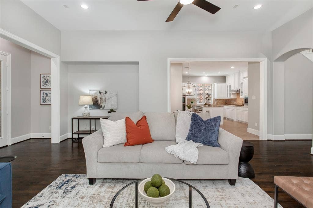 844 Veneto Drive, Allen, TX 75013 Family room open to the kitchen through a wide cased opening, with the stone fireplace and raisedhearth on the right. Plantation shutters and hand-scraped hardwoods complete the space.