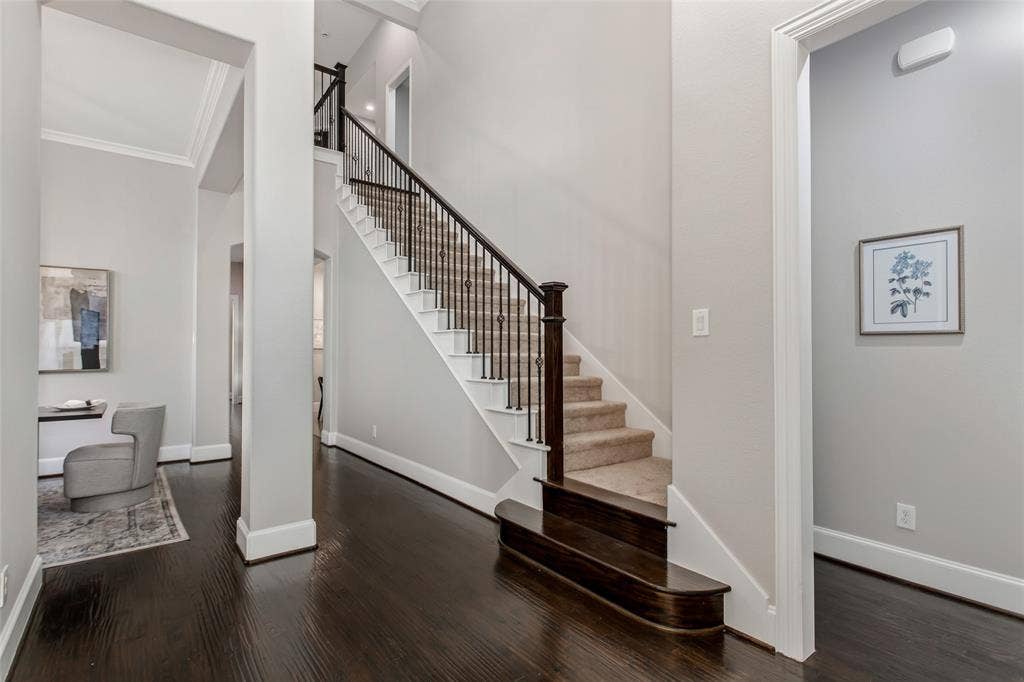 844 Veneto Drive, Allen, TX 75013 Staircase with wrought iron balusters, a stained wood newel post, and a rounded bullnose starter step.Treads carry new 2026 carpet, and walls are finished in 2026 interior paint.