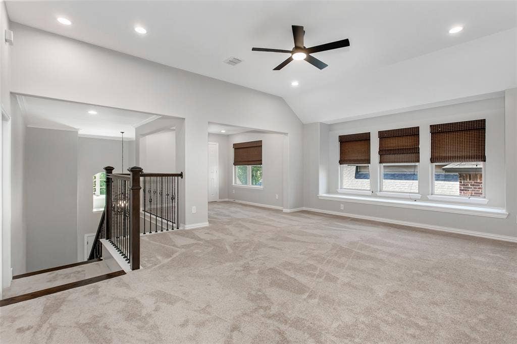 844 Veneto Drive, Allen, TX 75013 Upstairs game room with a vaulted ceiling, recessed lighting, and a new 2026 ceiling fan. A row of threewindows with a deep sill and an open overlook to the foyer staircase.