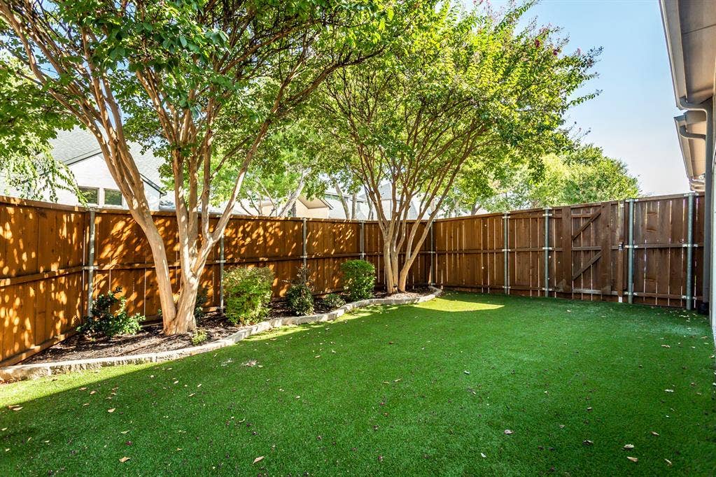 844 Veneto Drive, Allen, TX 75013 Turf yard shaded by mature crape myrtles with a stone-bordered landscape bed. Stained privacy fenceon steel posts with a gate to the side yard.