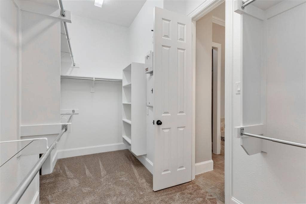 844 Veneto Drive, Allen, TX 75013 Walk-in closet with double hanging rods, built-in shelving, and new 2026 carpet. Opens directly to theprimary bath.