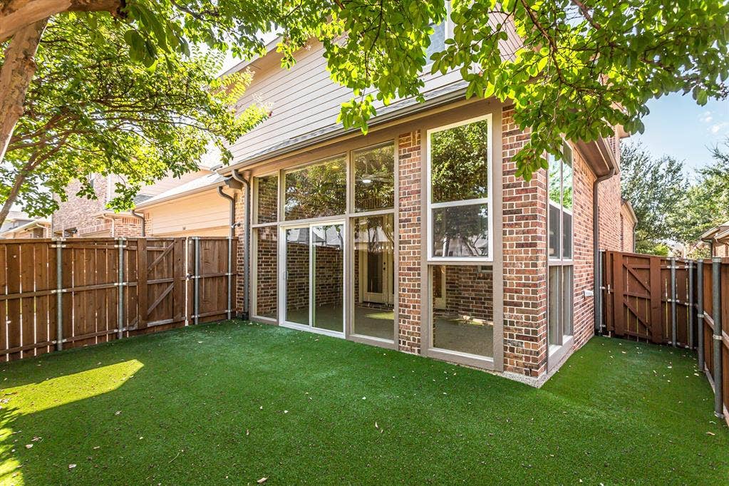 844 Veneto Drive, Allen, TX 75013 Rear elevation of brick and siding with the glass-enclosed sunroom opening to the turf yard through asliding door. Gated side yard access on both sides.
