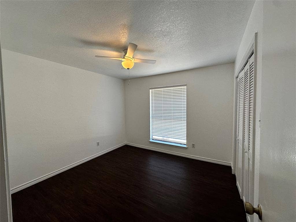 Wood-finish flooring, white walls, and a ceiling fan with integrated lighting