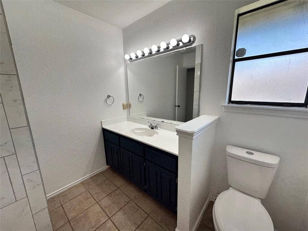 Vanity with a white countertop and integrated sink, dark cabinetry, and tile flooring