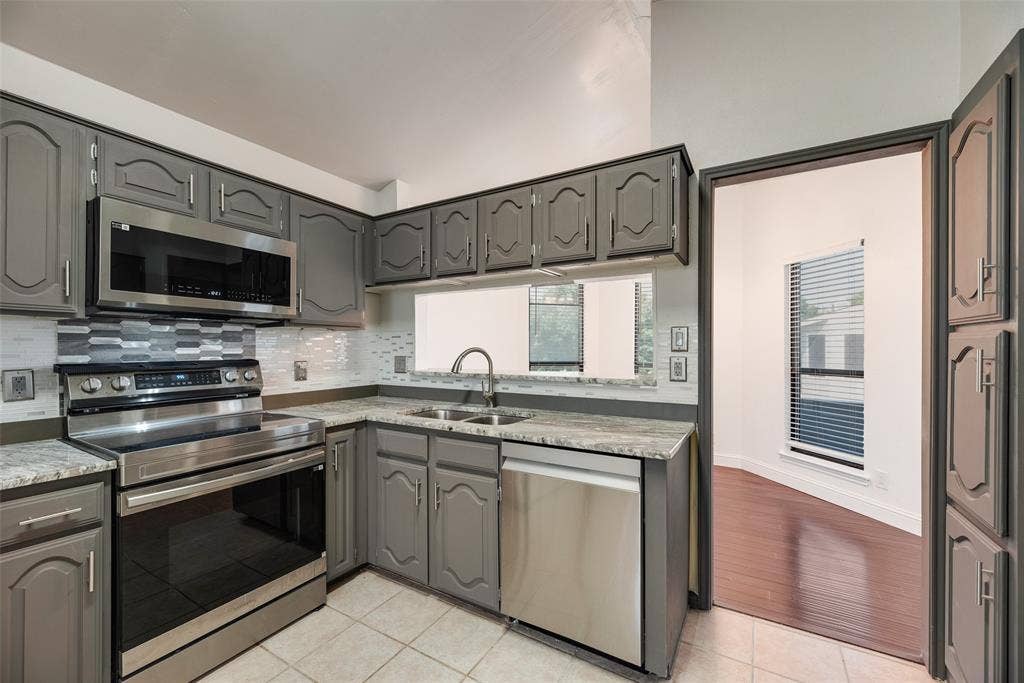 17490 Meandering Way, #202, Dallas, TX 75252 Kitchen featuring gray cabinetry, stainless steel appliances, a tile backsplash, and a double basin sink