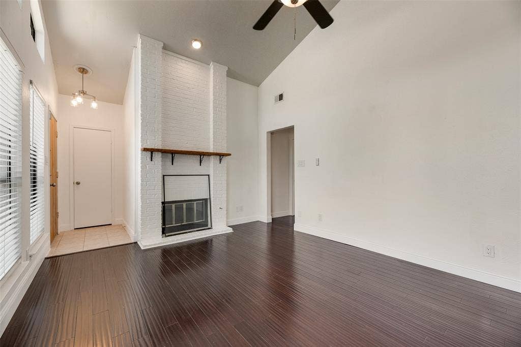 17490 Meandering Way, #202, Dallas, TX 75252 Vaulted ceiling with an installed ceiling fan, wood-finish flooring, a white brick fireplace with a wood mantle, and an entry with tile flooring