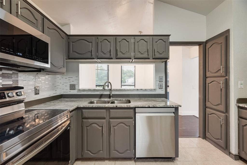 17490 Meandering Way, #202, Dallas, TX 75252 Kitchen featuring gray cabinetry, stainless steel appliances, granite-look countertops, and a mosaic tile backsplash