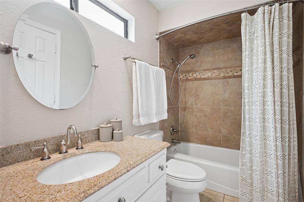 2001 Pebble Beach Court, Richardson, TX 75082 Ensuite bathroom features earthy toned granite counters, a decorative mirror, and tile tub surround.