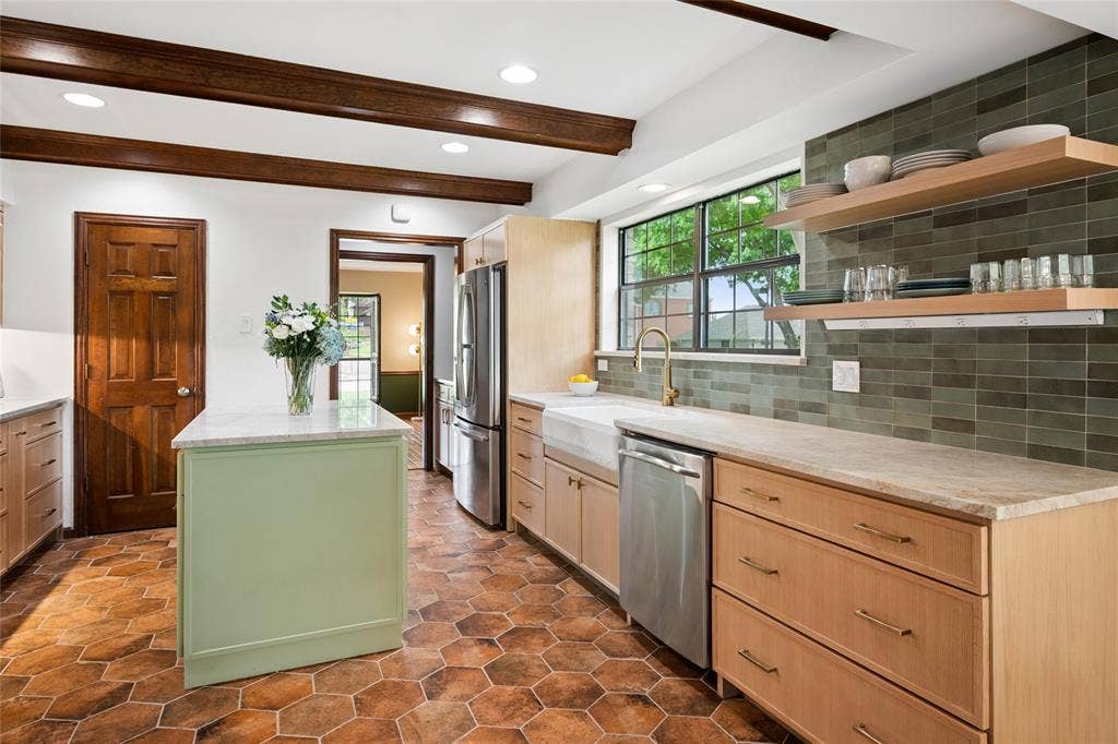 2001 Pebble Beach Court, Richardson, TX 75082 Fully updated in 2023, this kitchen echoes the natural beauty outside with green tile backsplash, wood beamed ceilings, and earthy toned tile floors.