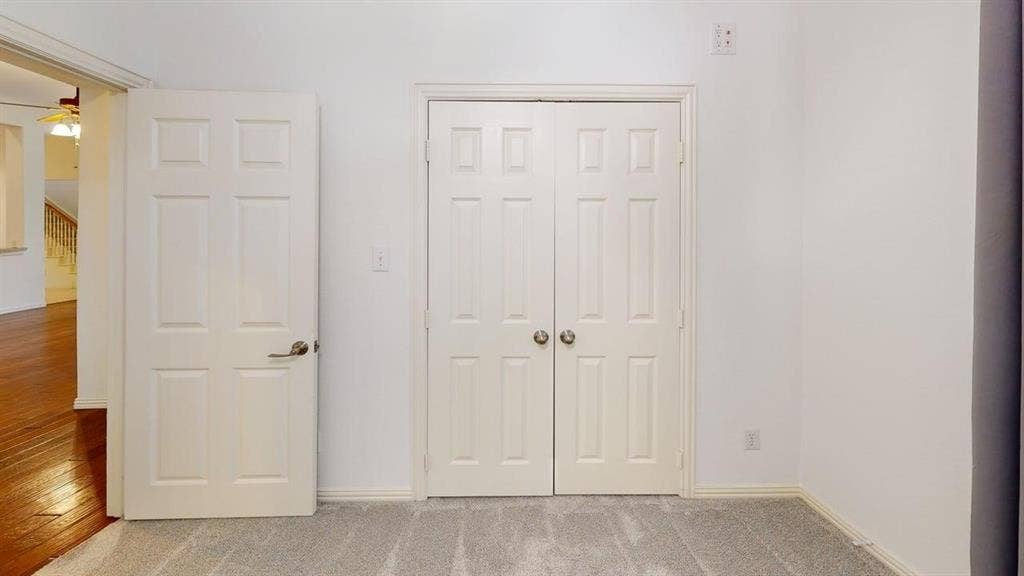 Light gray carpeting, white painted walls, white paneled doors, and brushed nickel hardware