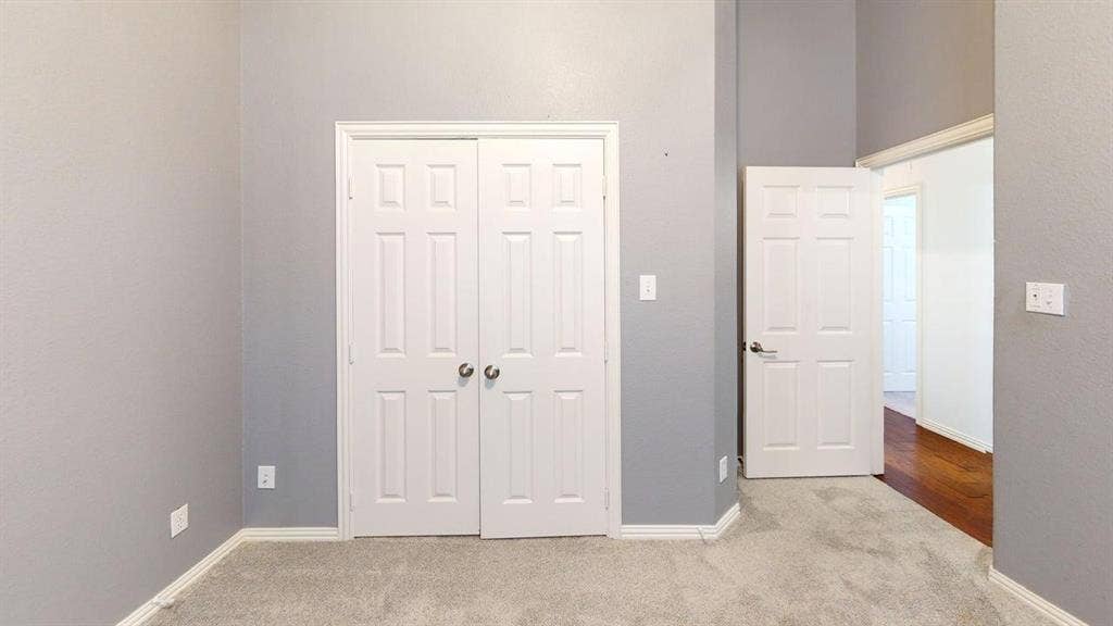 Neutral-toned walls, plush carpet flooring, white paneled doors, and white trim accents