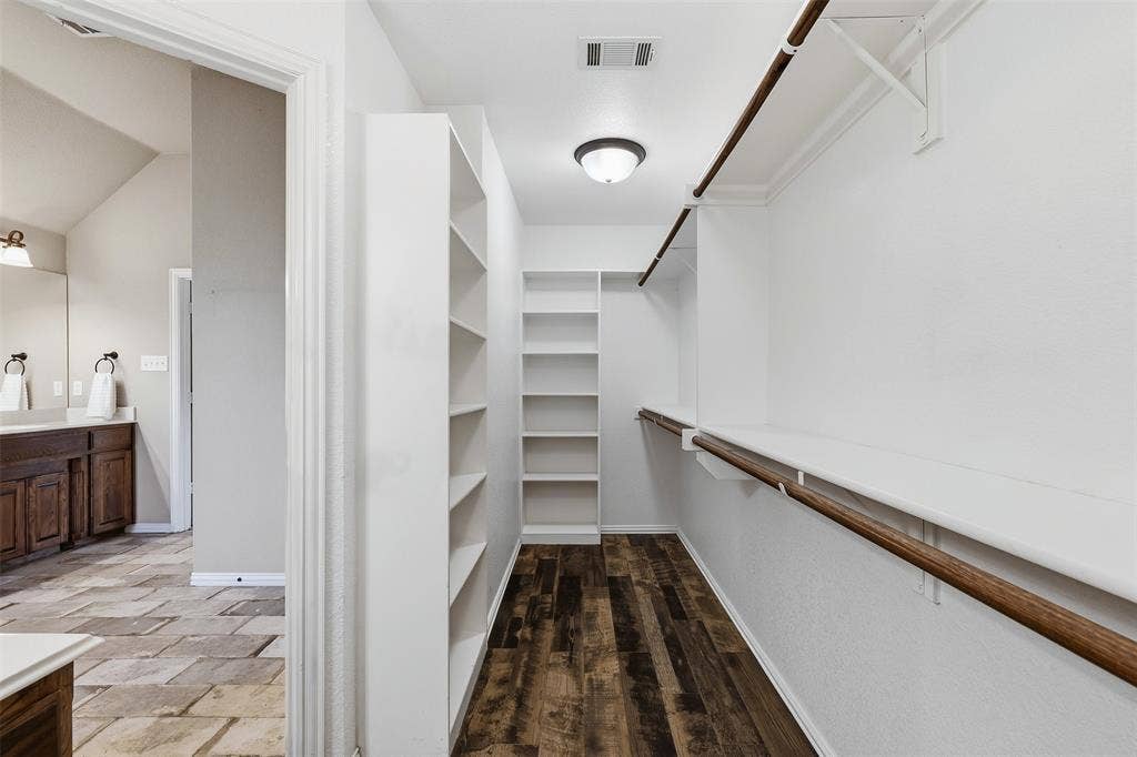 Walk-in closet with extensive built-in shelving, hanging rods, and wood-finish flooring