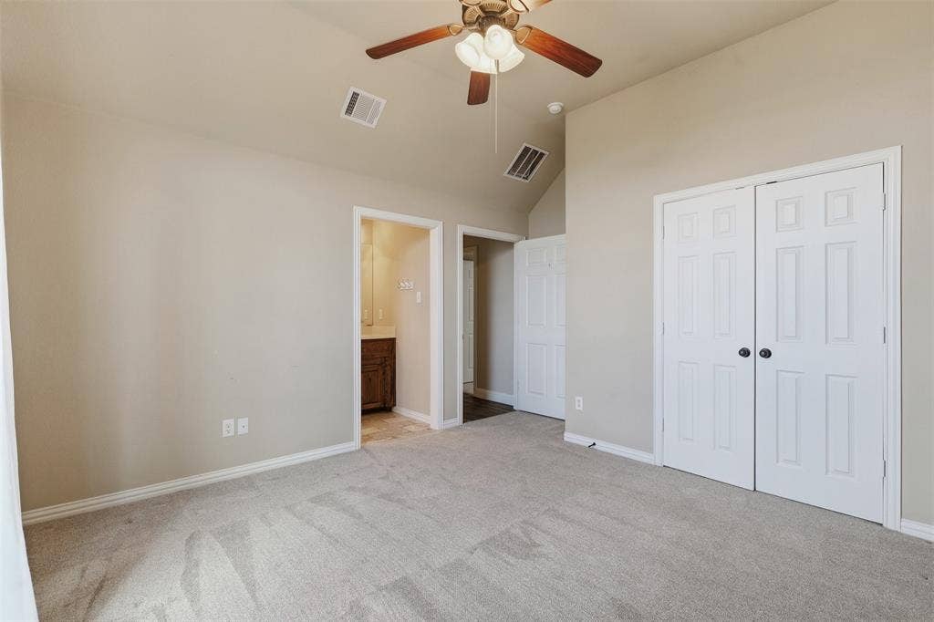 Vaulted ceiling with a ceiling fan, light gray carpeting, and paneled bifold closet doors