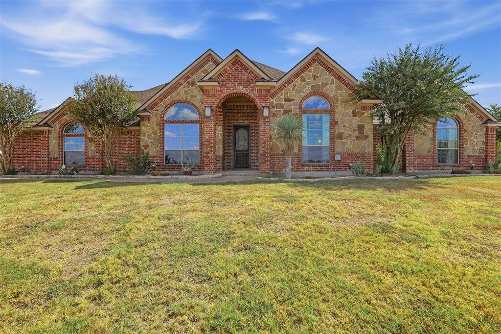 Brick and stone exterior with arched windows, prominent gables, and a covered entry