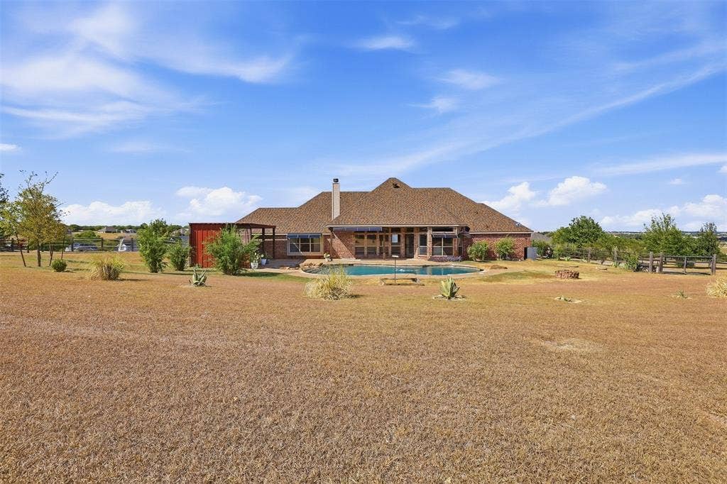 Brick exterior residence with an expansive backyard, featuring a swimming pool, covered patio, and attached pergola