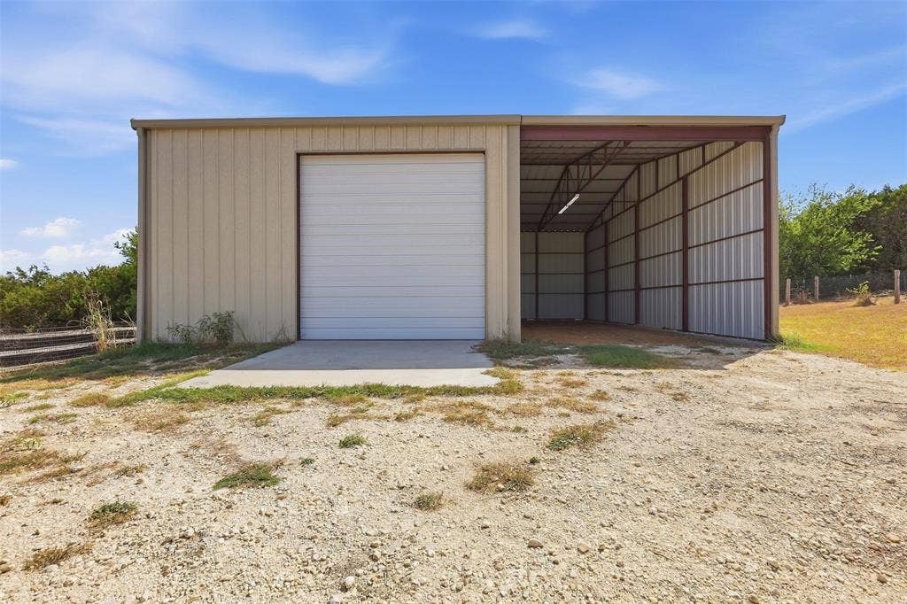 Metal building with roll-up door, exposed metal framework, and concrete pad