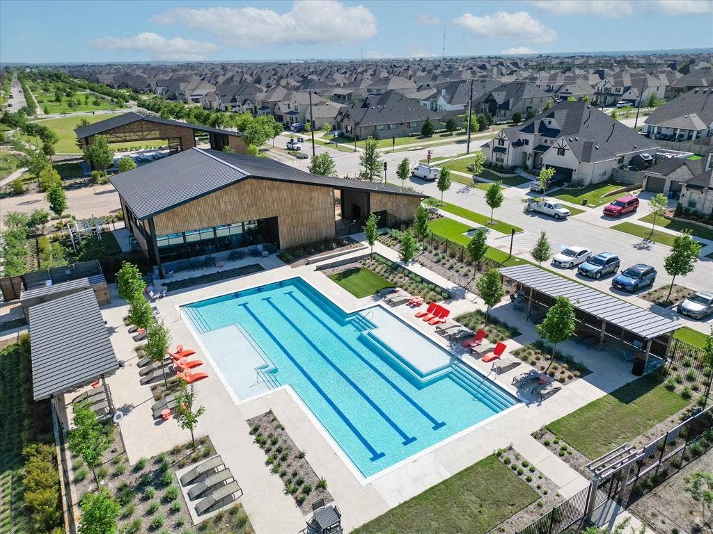 612 4th Street, Argyle, TX 76226 Community swimming pool with lap lanes, expansive concrete decking, multiple covered lounging areas, and a modern clubhouse with wood-finish siding