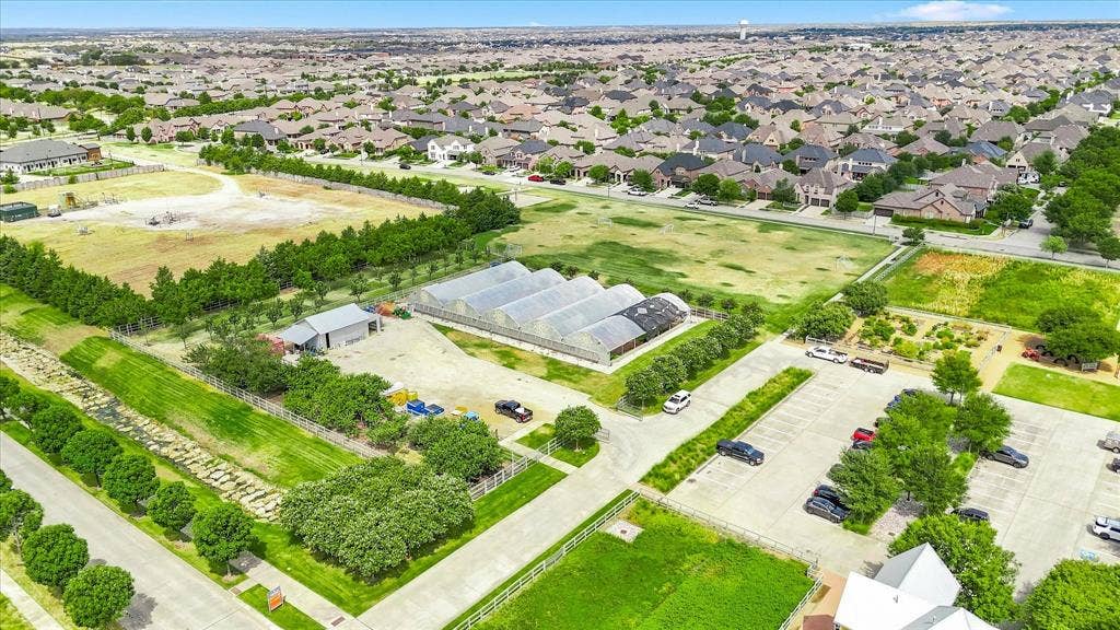 612 4th Street, Argyle, TX 76226 Expansive property featuring multiple greenhouses, a large parking area, and a utility building, surrounded by green spaces and mature trees