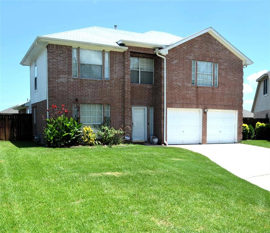 3994 Sword Dancer Way, Grand Prairie, TX 75052 Brick exterior with white siding accents, a two-car garage, a white entry door, and mature landscaping