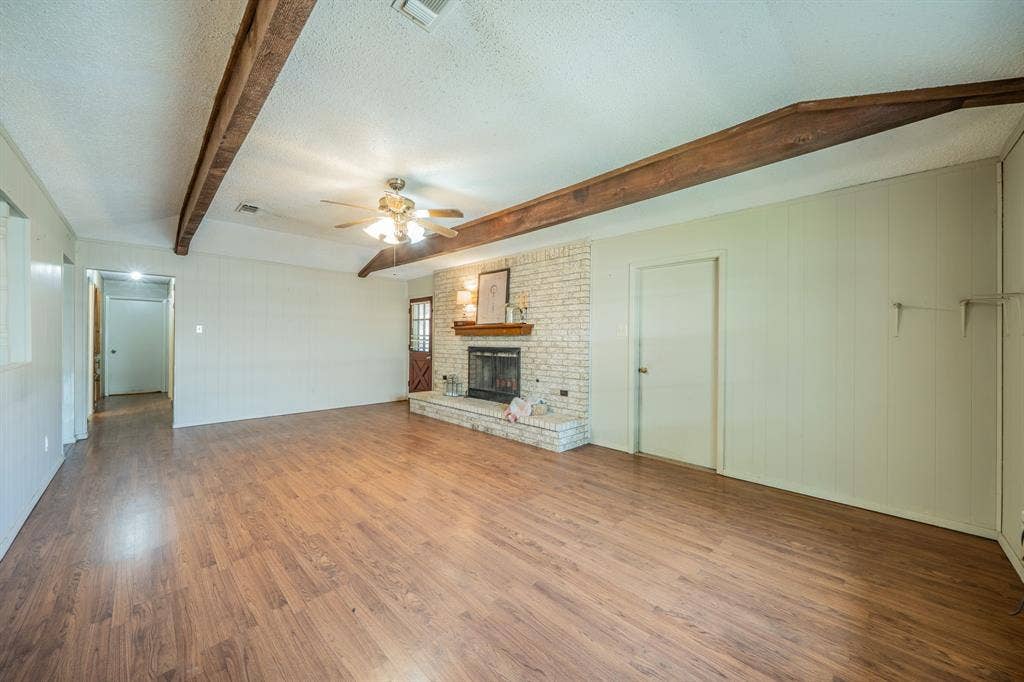 1517 Meadow Court, Midlothian, TX 76065 Expansive living area with wood-finish flooring, exposed ceiling beams, and a brick-faced fireplace