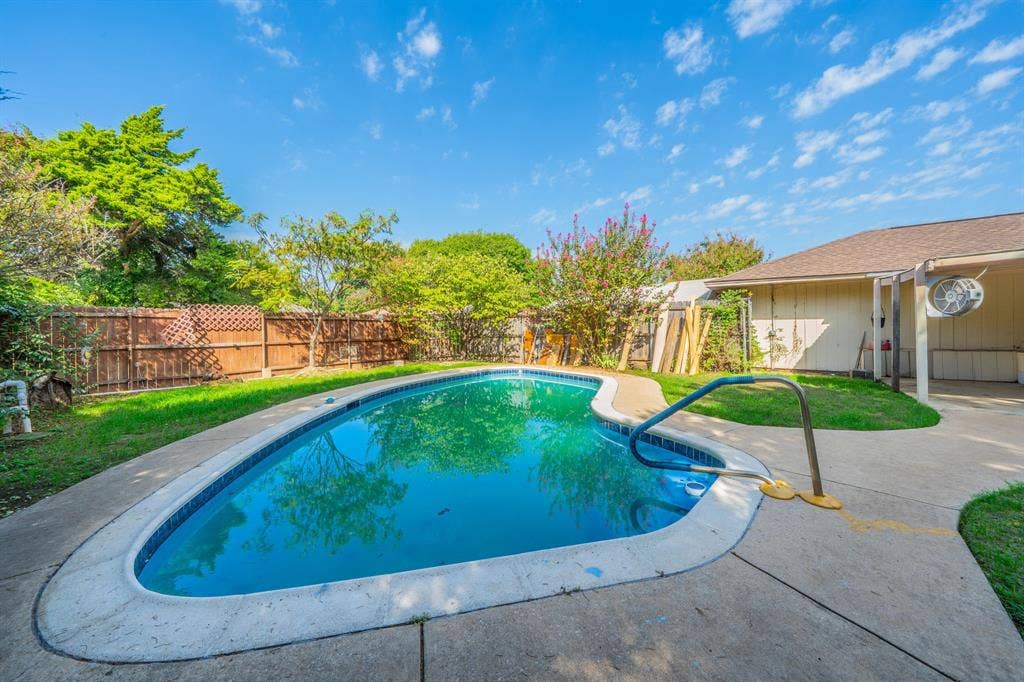 1517 Meadow Court, Midlothian, TX 76065 Curved swimming pool with a concrete surround, wood privacy fencing, and green lawn areas
