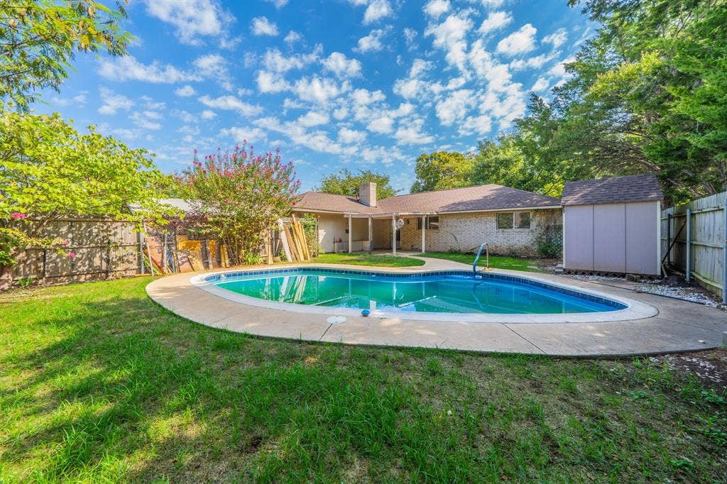 1517 Meadow Court, Midlothian, TX 76065 Backyard featuring a kidney-shaped swimming pool with concrete decking, surrounding grassy areas, and a wooden privacy fence