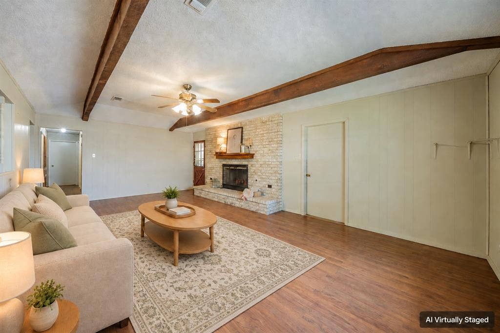 1517 Meadow Court, Midlothian, TX 76065 Living area featuring wood-finish flooring, exposed ceiling beams, and a stone-clad fireplace with a wood mantel